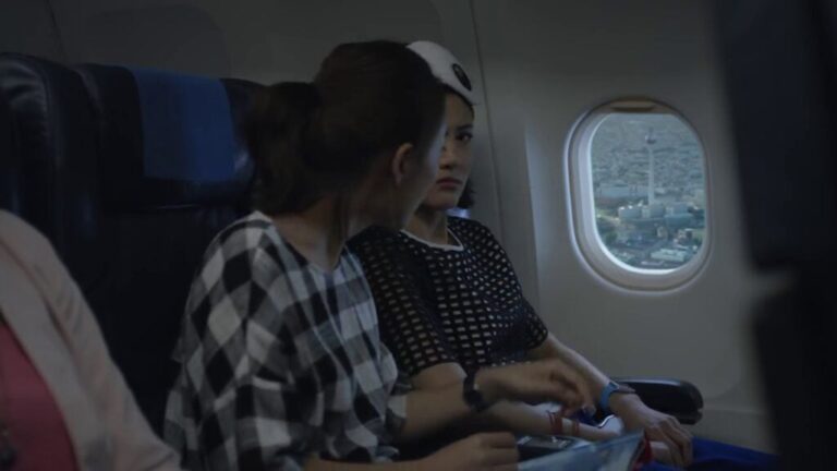 Passengers seated on an airplane looking out the window at Berlin, wearing an Apple Watch.