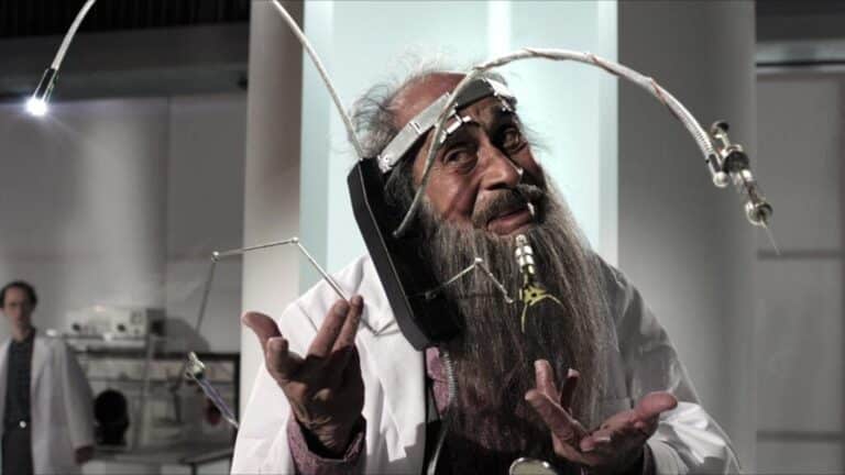 Elderly man wearing experimental communication headgear in a laboratory.