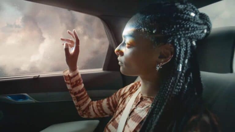 Woman sitting in the back seat of a car, light filtering through the window.