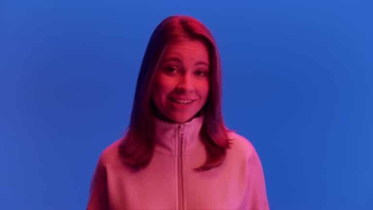 Person smiling against a colorful blue and pink background.