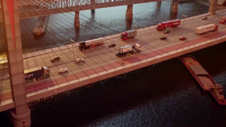 Trucks and cars cross a large bridge over a river.